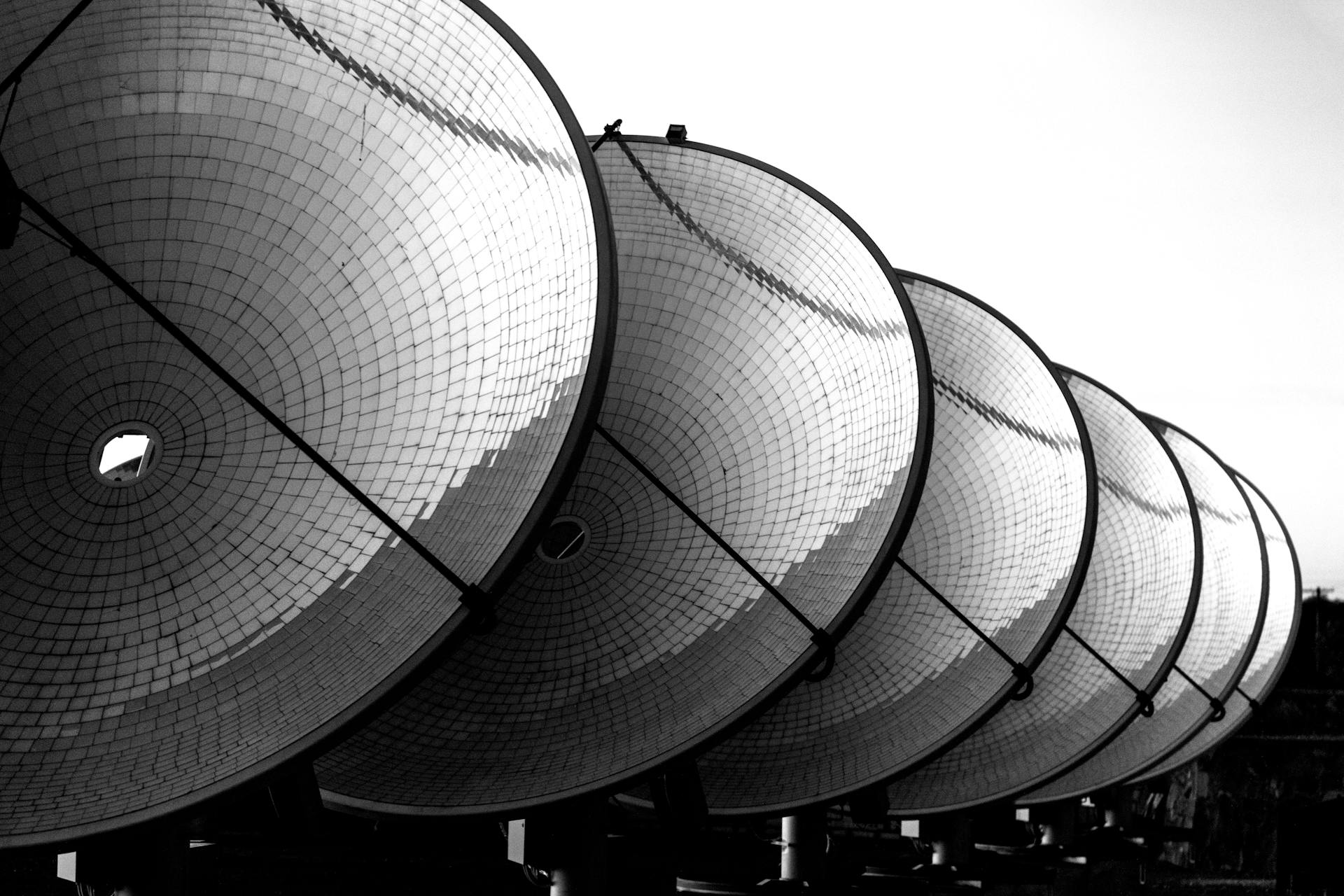 A line of six large solar dishes face towards the sun at thermal power station
