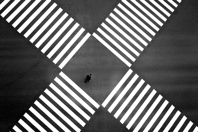 Aerial view of two zebra crossing crossroads overlapping with man in the middle